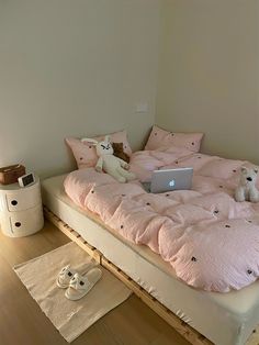 a laptop computer sitting on top of a bed in a room with wooden flooring