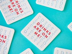 some white and red drink coasters on a blue surface with words written on them