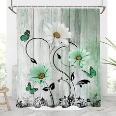 a shower curtain with white flowers and green butterflies on the wooden planked wall behind it