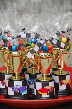 several trophies on a red tray with candy in them and some candies wrapped in cellophane