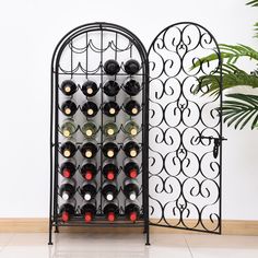 a wine rack with many bottles in it next to a potted plant and white wall