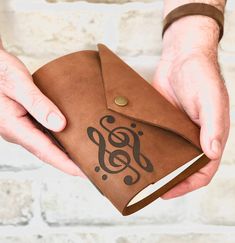 a person holding an open brown leather journal