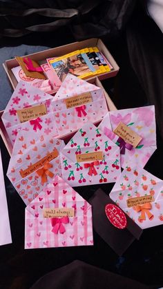 some pink and red cards in a box on a black surface with other items around them