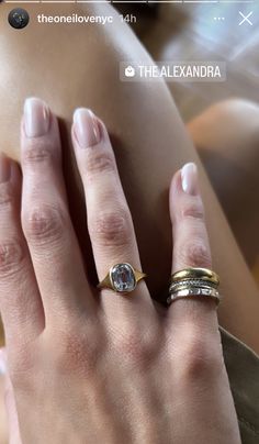 a woman's hand with two gold rings on her left and an engagement ring on her right