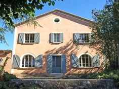 a pink house with shutters on the windows and blue shutters in front of it