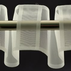 three white mesh curtains hanging from a metal rod