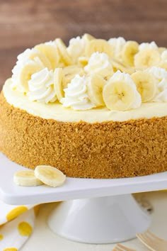 a cake with bananas and whipped cream on top is sitting on a white platter