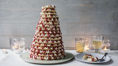 a large stack of cookies sitting on top of a table next to plates and glasses