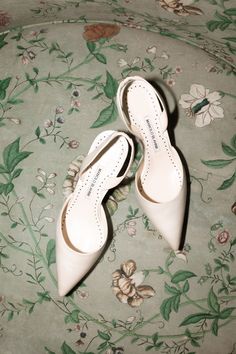 two pairs of white shoes sitting on top of a floral print chair cushioned area