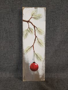 a red ornament hanging from a tree branch on a gray fabric wall panel