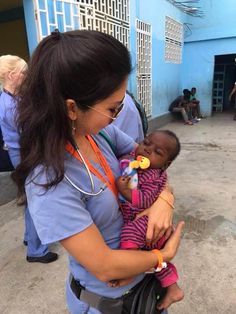 a woman holding a baby in her arms and wearing a stethoscope on it's face