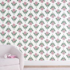 a white chair sitting in front of a wall with pink flowers on it's side