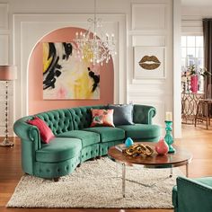 a living room filled with green couches and a chandelier hanging from the ceiling