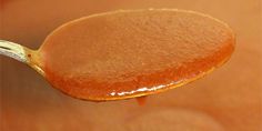 a close up of a spoon full of honey on a wooden table with blurry background