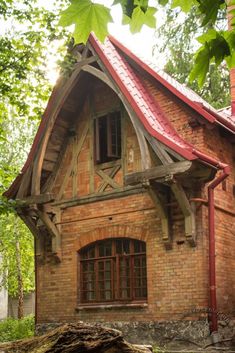 an old brick house with red roof and window frames on the outside, surrounded by trees