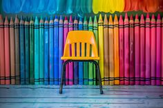 a yellow chair sitting in front of colored pencils