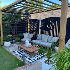 an outdoor living area with couches, tables and potted plants