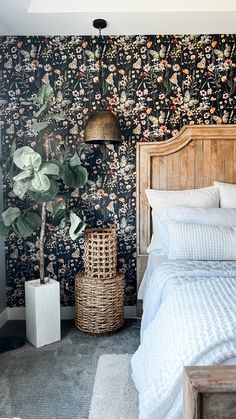 a bedroom with floral wallpaper and wooden headboard, white bedding, and wicker basket on the floor