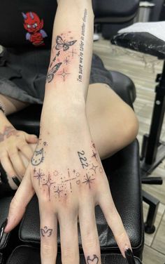 a woman's hand with tattoos on it sitting in front of a black chair