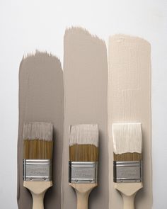 three paintbrushes with different shades of gray and beige on them, one is white