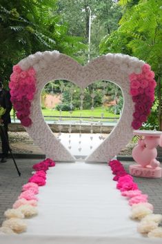 a white table topped with pink flowers and a heart shaped frame on top of it