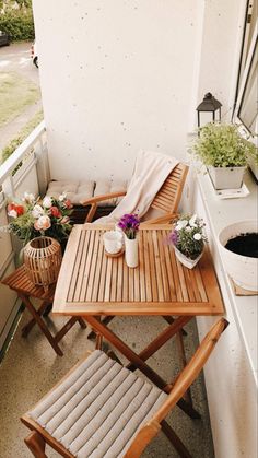 two wooden chairs sitting next to each other on top of a balcony with potted plants