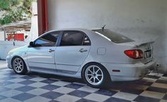 a white car parked in front of a building with a checkered floor and walls