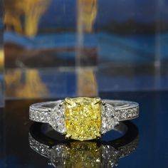 a fancy yellow diamond ring sitting on top of a table