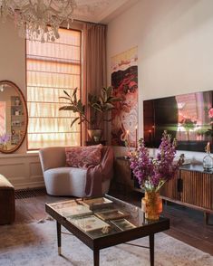 a living room filled with furniture and a chandelier hanging from the ceiling next to a window