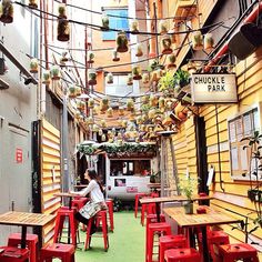 an alleyway with tables and red chairs