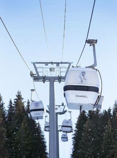 a ski lift with two people on it going up the mountain in front of some trees