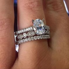 a woman's hand with two wedding bands and a ring on top of her finger