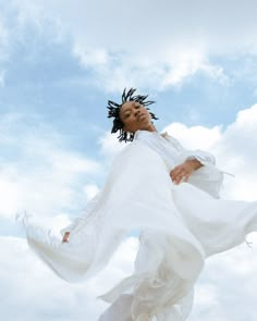 a woman flying through the air while wearing a white dress