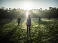 a group of people standing on top of a lush green field