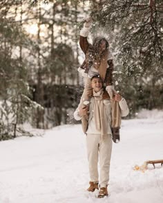 a woman walking through the snow carrying an animal on her back