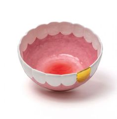 a pink and white bowl with yellow handles