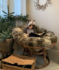 a young child sitting in a chair reading a book