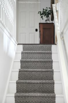 the stairs are decorated with black and white rugs, along with a potted plant