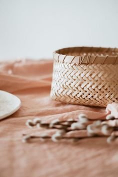 a woven basket sitting on top of a bed next to a white plate and spoon