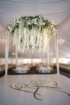 a large white tent with chandeliers and flowers on the dance floor at a wedding reception