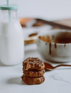 three cookies sitting on top of a table next to a glass of milk