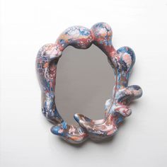 a mirror that is on the wall with paint splattered over it and in the shape of an animal's paw