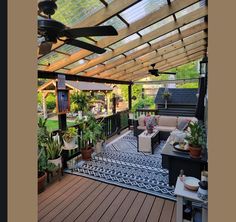 an outdoor living area with couches, tables and plants on the deck under a pergolated roof