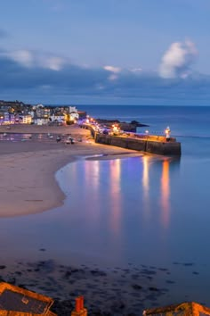 the beach is lit up at night with buildings in the background