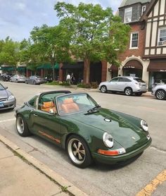 a green sports car parked on the side of the road in front of other cars