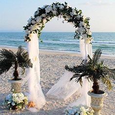 an outdoor wedding setup on the beach with palm trees and white flowers in vases