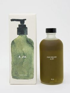 a bottle of soap next to a box on a white surface with a green and black design