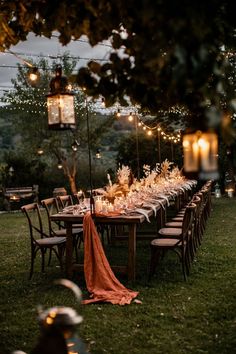 an outdoor dinner table set up with candles and flowers