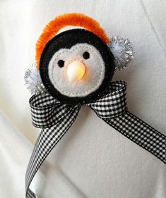 a stuffed penguin with an orange hat and black checkered ribbon on it's head