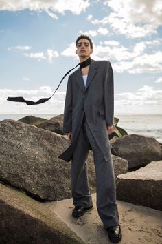 a man in a suit and tie standing on some rocks